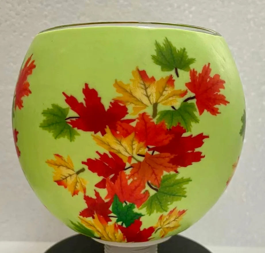 Maple Leaves Claymaster light globe on a dark pedestal base with red, orange and yellow maple leaves on a lime-green background